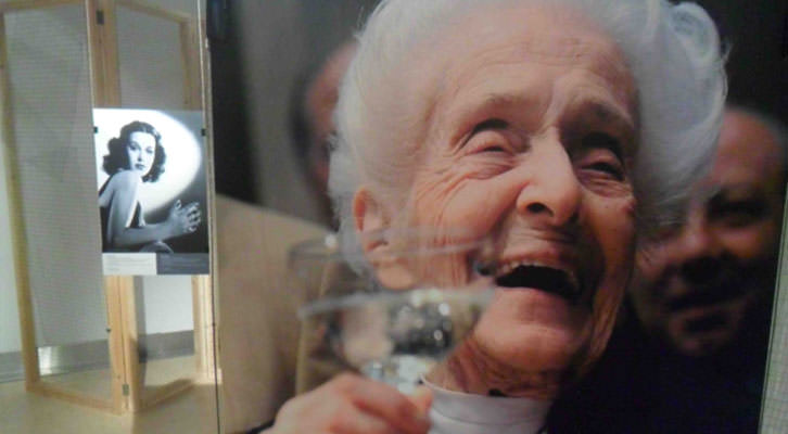 Fotografía de Rita Levi-Montalcini, sonriente, en la exposición 'Trencant barrees. Dones i ciències' que acoge el Palau de Cerveró.