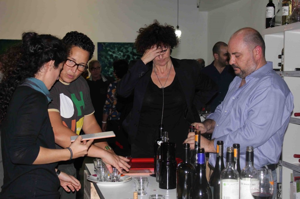 Rosa Guillem, responsable de Espacio 40, se echa las manos a la cabeza, mientras José Antonio Ruiz, de Vinos de Chile, abre una botella durante la inauguración de la exposición de Iñaki Torres. 