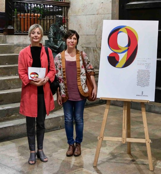 Marisa Gallén y Carmina Ibáñez junto al cartel diseñado por ellas. Imagen cortesía de las autoras. 