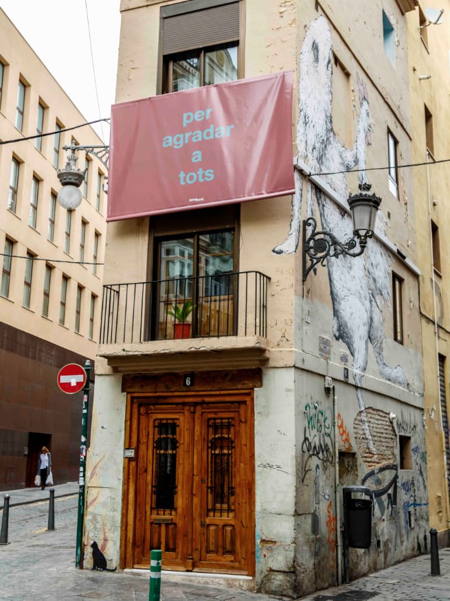 Obra de Fernando Baena colgada en un balcón entre la Calle Alta y la Calle Baja de Valencia. Foto de Enrique Miravalls por cortesía de Intramurs.