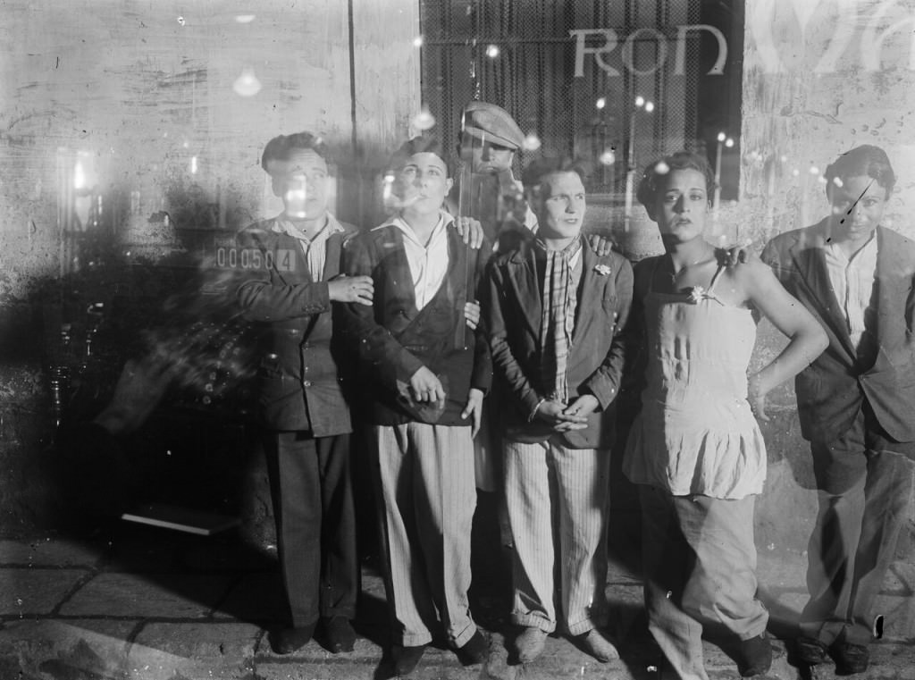 Imagen de 'Travestidos en una calle, vistos a través del vidrio de un bar, en el distrito 5, conocido popularmente  como el barrio Chino, en Barcelona', de Gabriel Casas. Fotografía cortesía de Núria Casas i Formiguera y Archivo Nacional de Catalu ña.