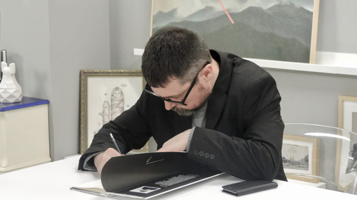 Pablo Amargo firmando un ejemplar de su libro, durante la entrevista con motivo de su exposición 'Cats are paradoxes', en Pepita Lumier. Foto: Javier Martínez